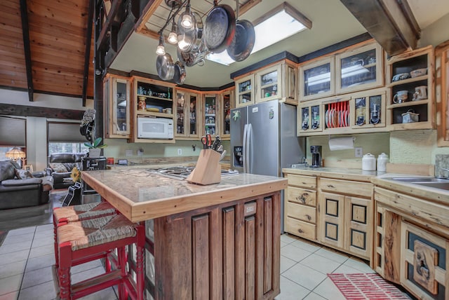 kitchen featuring stainless steel appliances, lofted ceiling with beams, a center island, an inviting chandelier, and light tile patterned floors