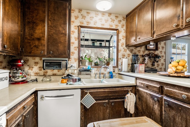 kitchen featuring dark brown cabinets, white dishwasher, and sink