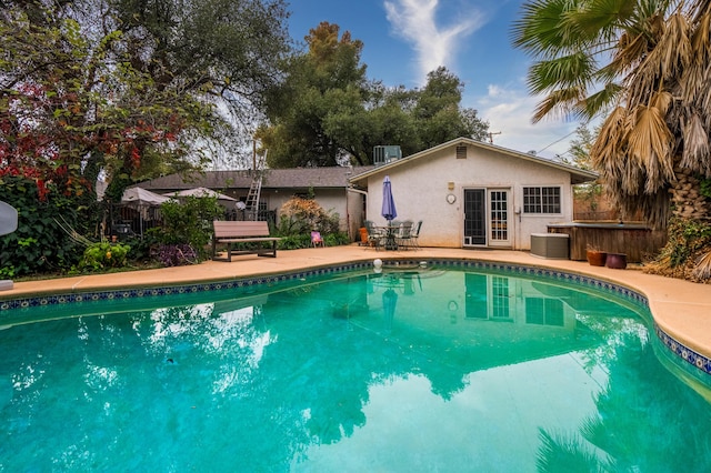 view of swimming pool with a jacuzzi, a patio area, french doors, and central AC