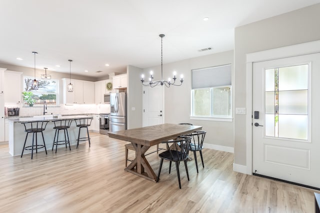 dining space with an inviting chandelier, light hardwood / wood-style flooring, and sink