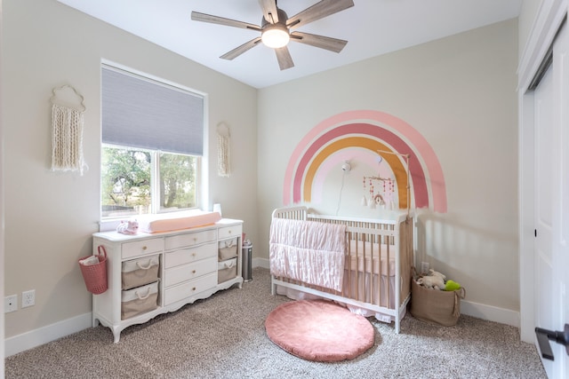 carpeted bedroom with a closet, a crib, and ceiling fan