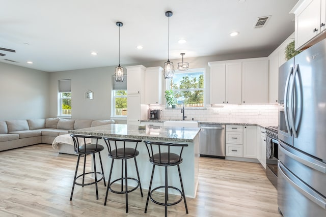 kitchen with white cabinetry, appliances with stainless steel finishes, a wealth of natural light, and decorative light fixtures