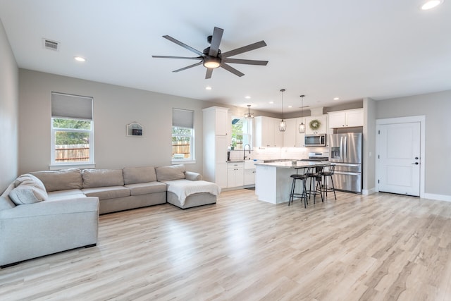 living room featuring light hardwood / wood-style floors, sink, and ceiling fan