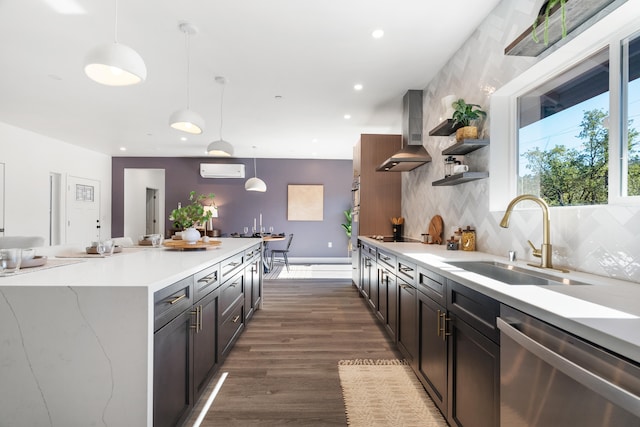 kitchen with sink, dishwasher, an AC wall unit, wall chimney exhaust hood, and pendant lighting