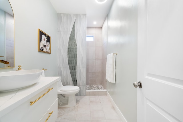 bathroom with a tile shower, vanity, and toilet