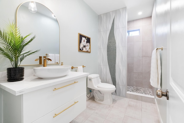 bathroom featuring vanity, toilet, tile patterned floors, and tiled shower