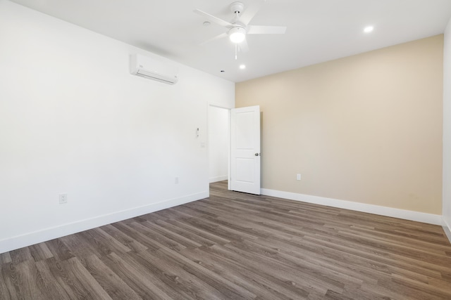 spare room featuring ceiling fan, a wall mounted AC, and dark hardwood / wood-style floors