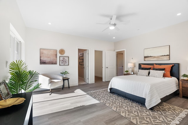 bedroom featuring ceiling fan, a walk in closet, and hardwood / wood-style floors