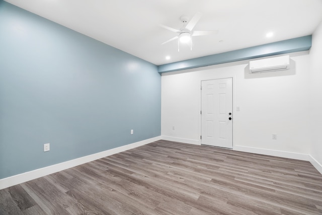 empty room with a wall unit AC, hardwood / wood-style floors, and ceiling fan