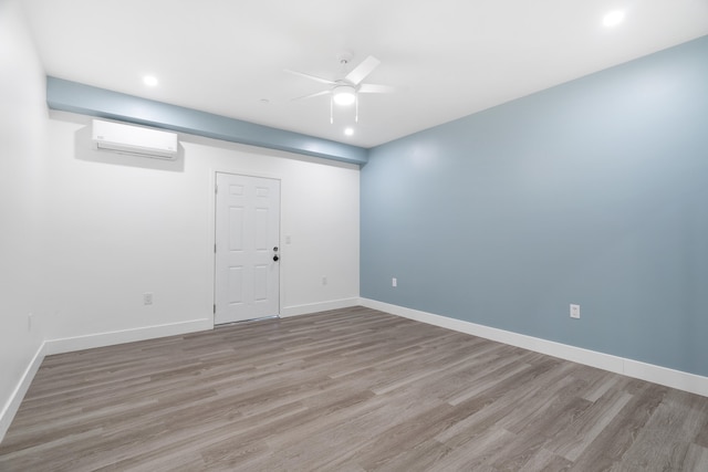 unfurnished room with ceiling fan, a wall mounted AC, and light wood-type flooring