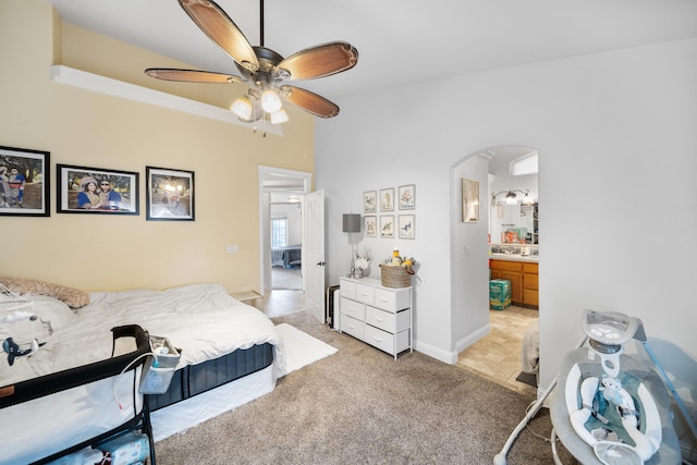 carpeted bedroom featuring ensuite bathroom, ceiling fan, and ornamental molding