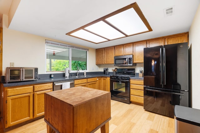 kitchen with sink, black appliances, light hardwood / wood-style flooring, and a center island