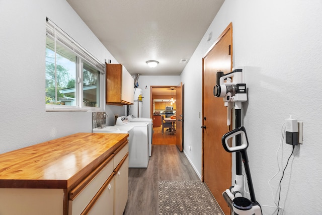 washroom with a textured ceiling, wood-type flooring, cabinets, and separate washer and dryer