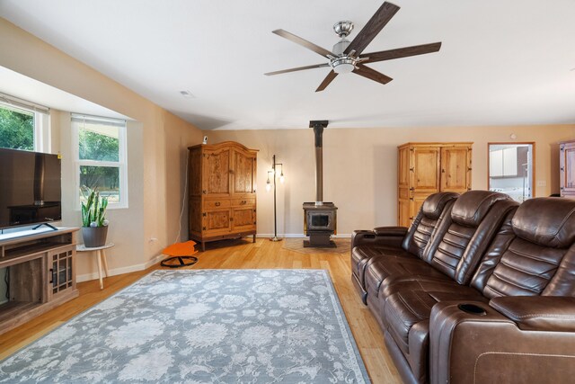 living room featuring light hardwood / wood-style floors, a wood stove, and ceiling fan