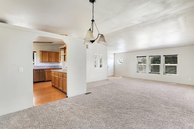 kitchen with light carpet, dishwasher, decorative light fixtures, and a textured ceiling