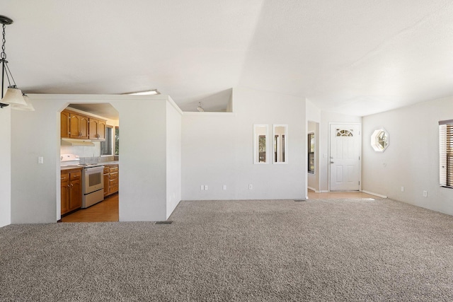 unfurnished living room featuring light carpet and vaulted ceiling