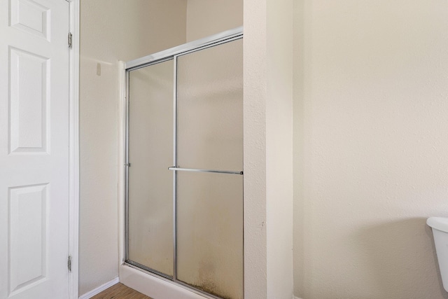 bathroom featuring a shower with door and toilet