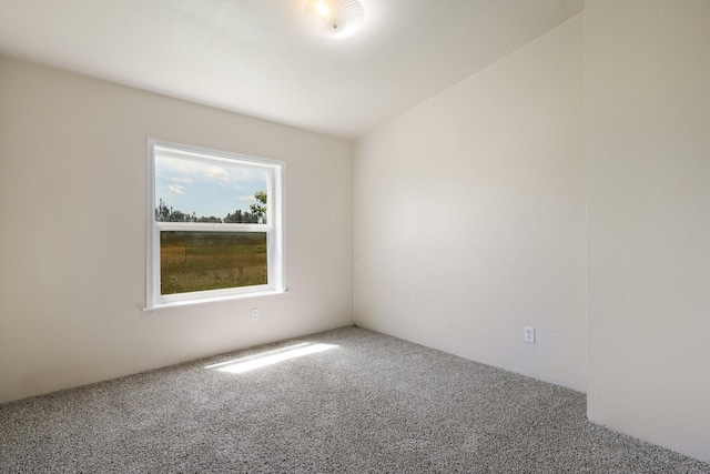 carpeted spare room with vaulted ceiling