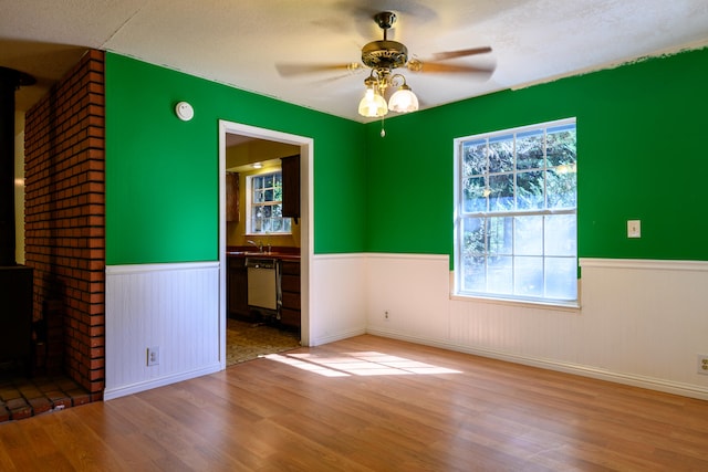 empty room featuring a wood stove, a textured ceiling, and wood-type flooring