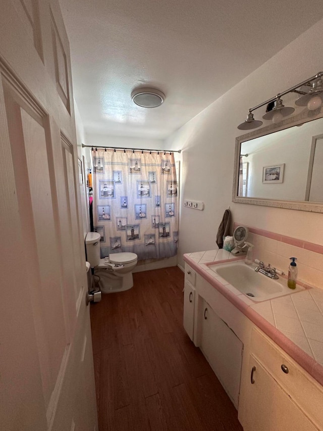 bathroom featuring curtained shower, wood-type flooring, vanity, and toilet