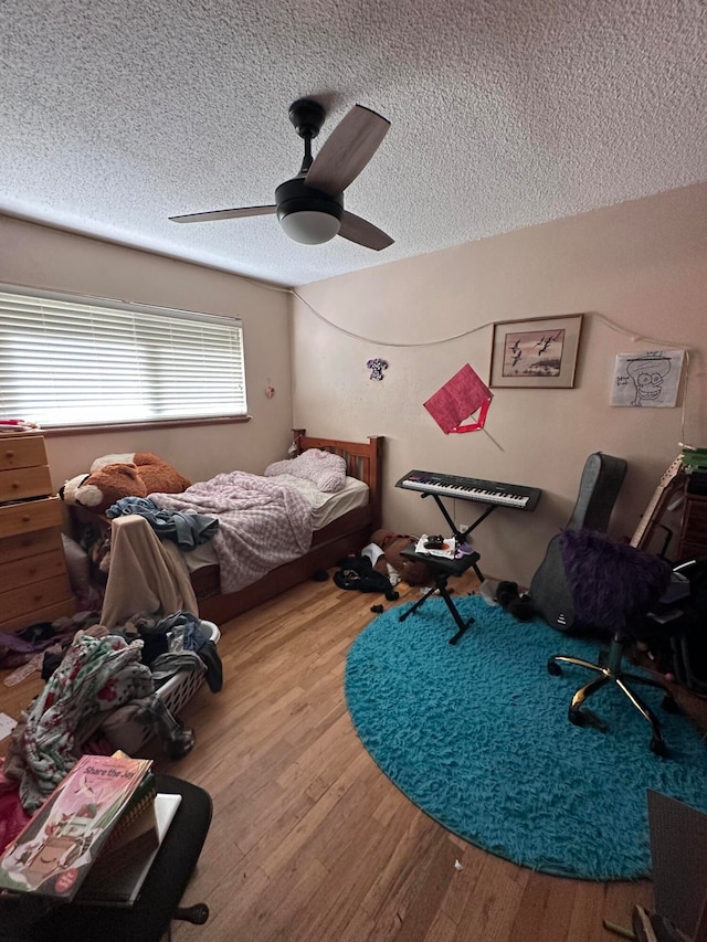 bedroom with hardwood / wood-style flooring, ceiling fan, and a textured ceiling