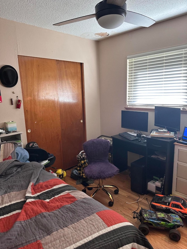 bedroom with hardwood / wood-style floors, ceiling fan, and a textured ceiling