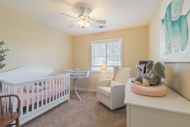 bedroom with a crib, light colored carpet, and ceiling fan