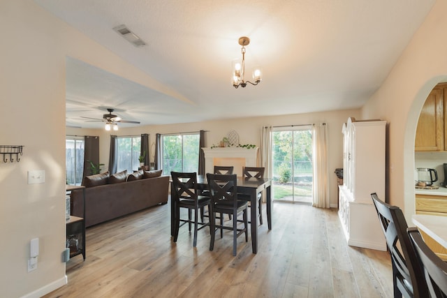 dining space featuring ceiling fan with notable chandelier, light wood-type flooring, and a wealth of natural light