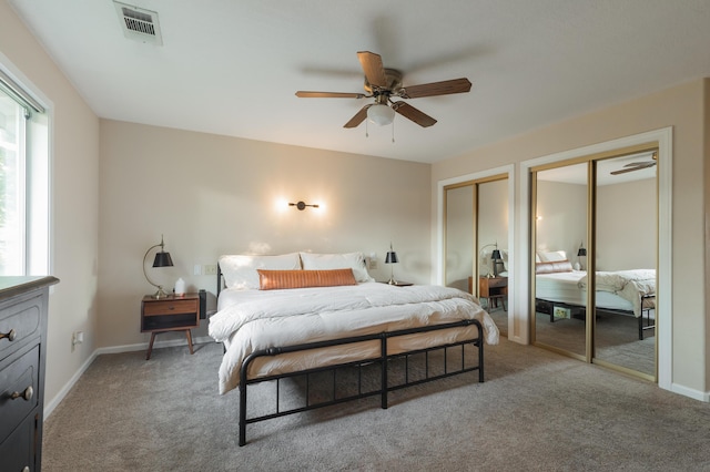 carpeted bedroom with two closets and ceiling fan