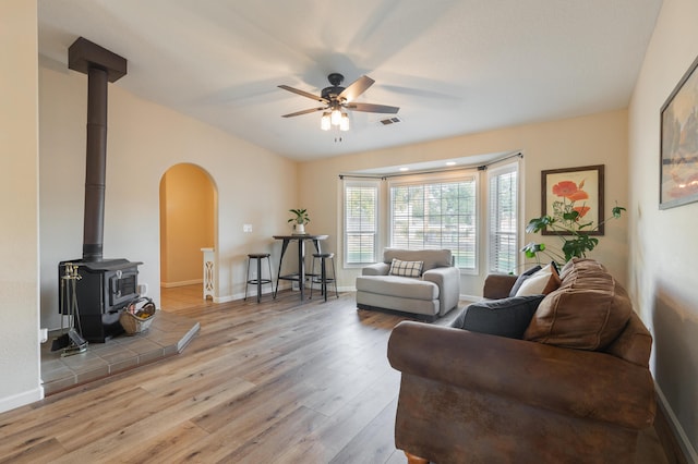 living room featuring a wood stove, ceiling fan, and light wood-type flooring