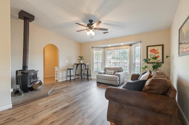 3182 Island Dr, Redding, CA 96001 - living area with a wood stove, ceiling fan, arched walkways, and light wood-style flooring