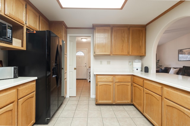 kitchen with light tile patterned flooring, black fridge, ornamental molding, and washer / clothes dryer