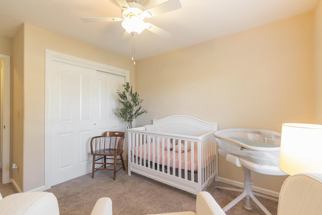 bedroom featuring ceiling fan, light colored carpet, a nursery area, and a closet