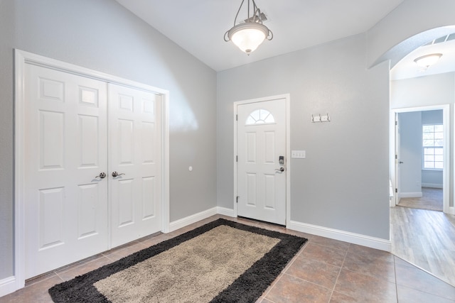 foyer featuring tile patterned flooring and vaulted ceiling