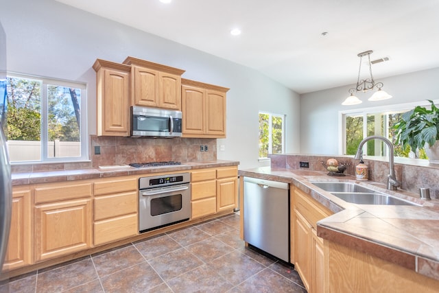 kitchen featuring stainless steel appliances, sink, tasteful backsplash, light brown cabinets, and a notable chandelier