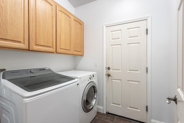 laundry room with cabinets, washing machine and dryer, and dark tile patterned flooring