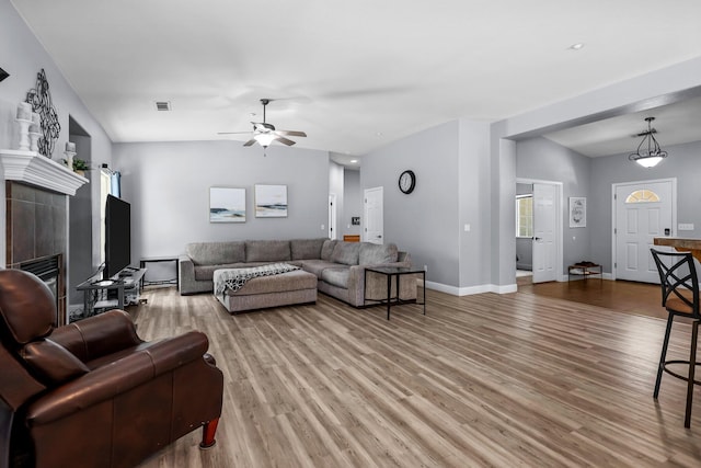 living room with light wood-type flooring, visible vents, a ceiling fan, and baseboards