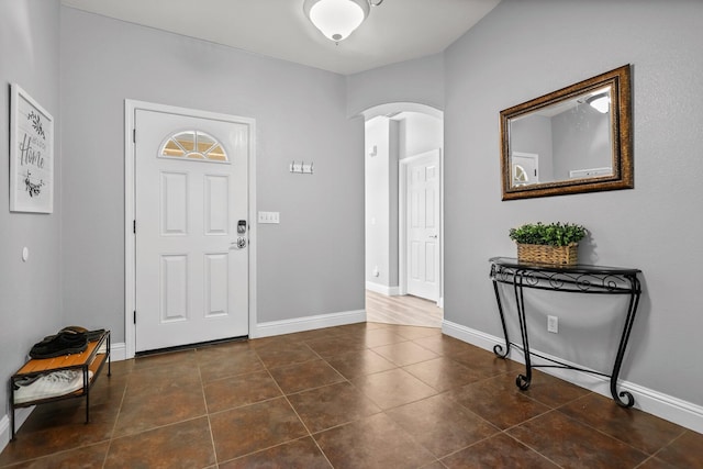 entrance foyer with dark tile patterned flooring, baseboards, and arched walkways