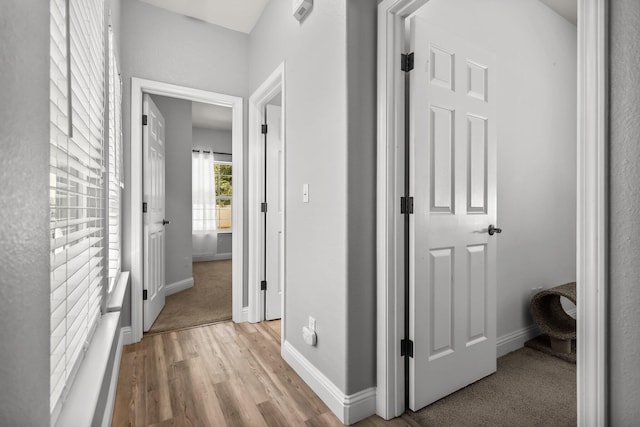 corridor with light wood finished floors and baseboards