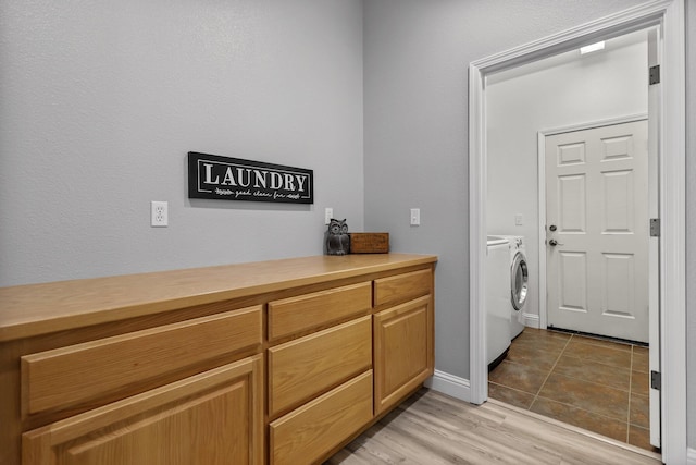 clothes washing area with washing machine and dryer, light wood-type flooring, baseboards, and laundry area