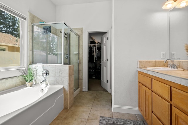 bathroom featuring tile patterned flooring, vanity, a walk in closet, a garden tub, and a stall shower