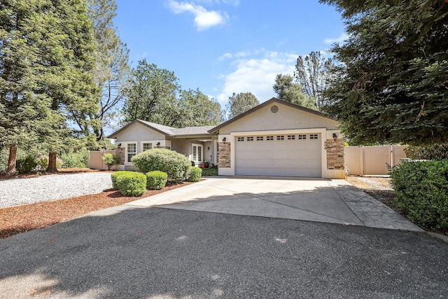 ranch-style house featuring an attached garage, fence, stucco siding, and driveway