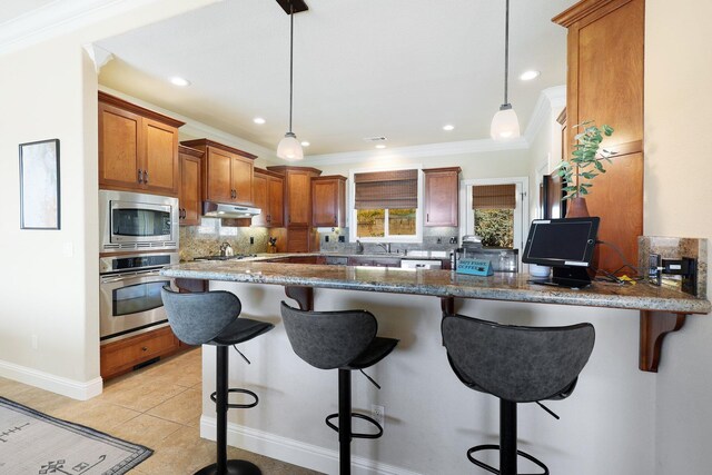 kitchen with kitchen peninsula, pendant lighting, stainless steel appliances, and a breakfast bar