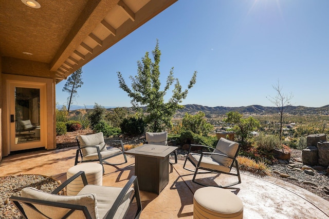 view of patio with a mountain view and an outdoor living space with a fire pit