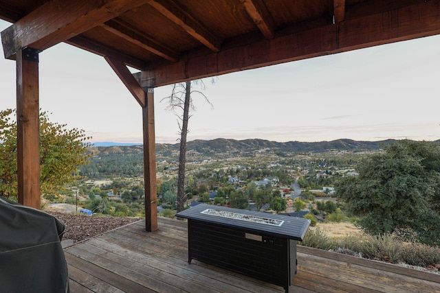 wooden terrace with a mountain view, an outdoor fire pit, and grilling area