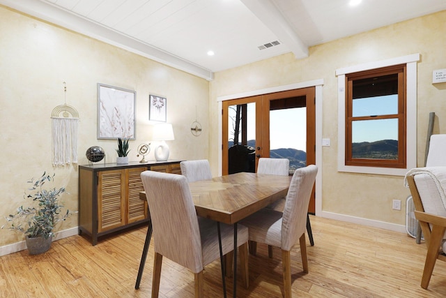 dining room with beamed ceiling, french doors, and light wood-type flooring