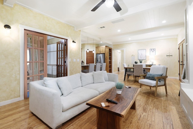 living room featuring beam ceiling, light hardwood / wood-style floors, and ceiling fan