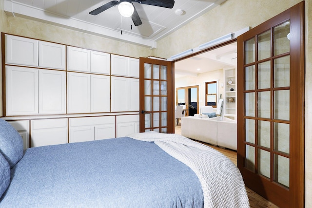 bedroom with french doors, hardwood / wood-style flooring, ceiling fan, and a tray ceiling