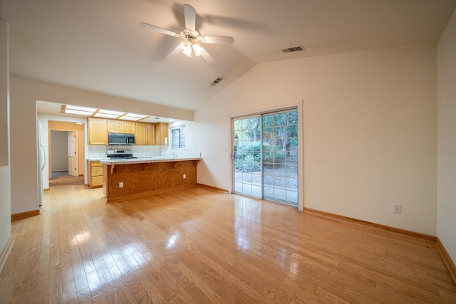 kitchen with light hardwood / wood-style flooring, vaulted ceiling, ceiling fan, stainless steel range oven, and kitchen peninsula