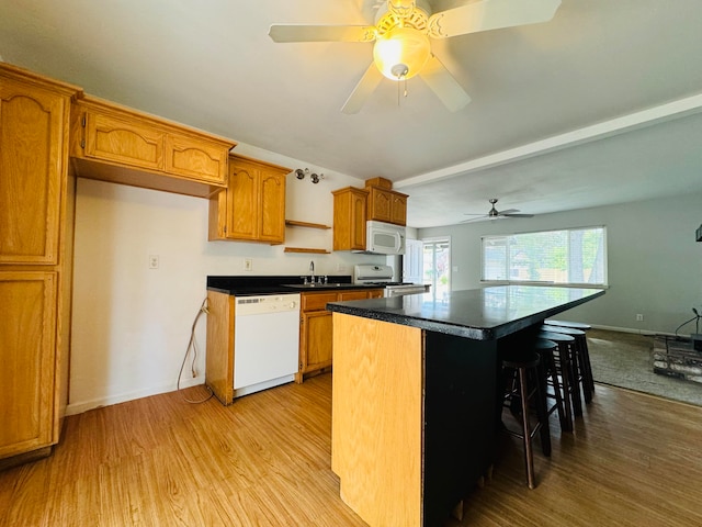 kitchen featuring a center island, a kitchen breakfast bar, ceiling fan, light hardwood / wood-style flooring, and white appliances